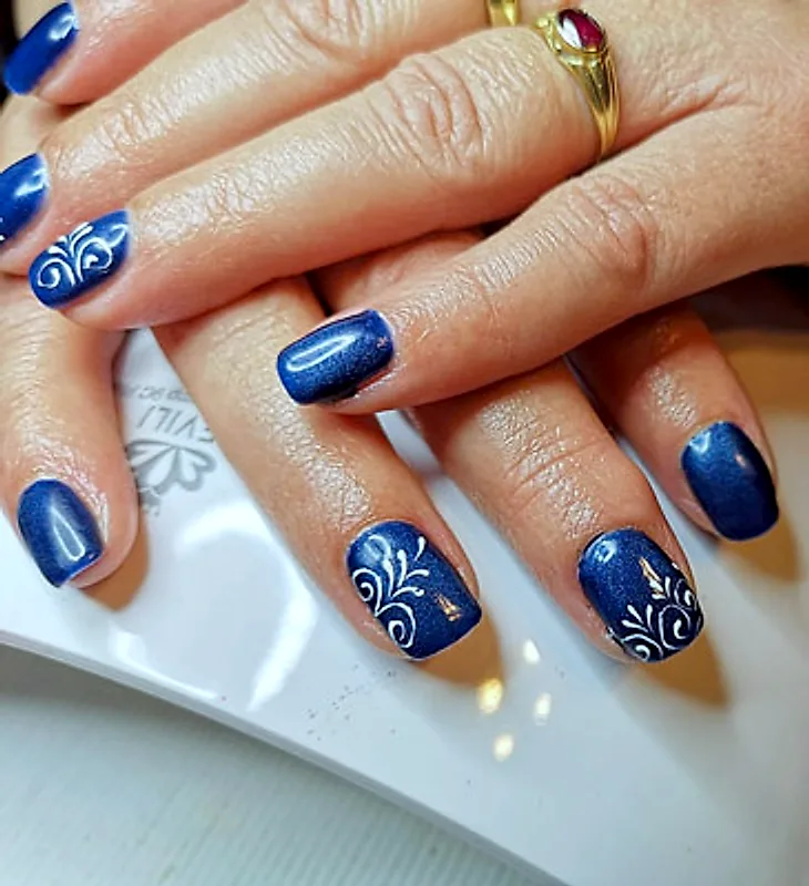 Dunkelblaue Kunstnägel mit weißen Ornamenten