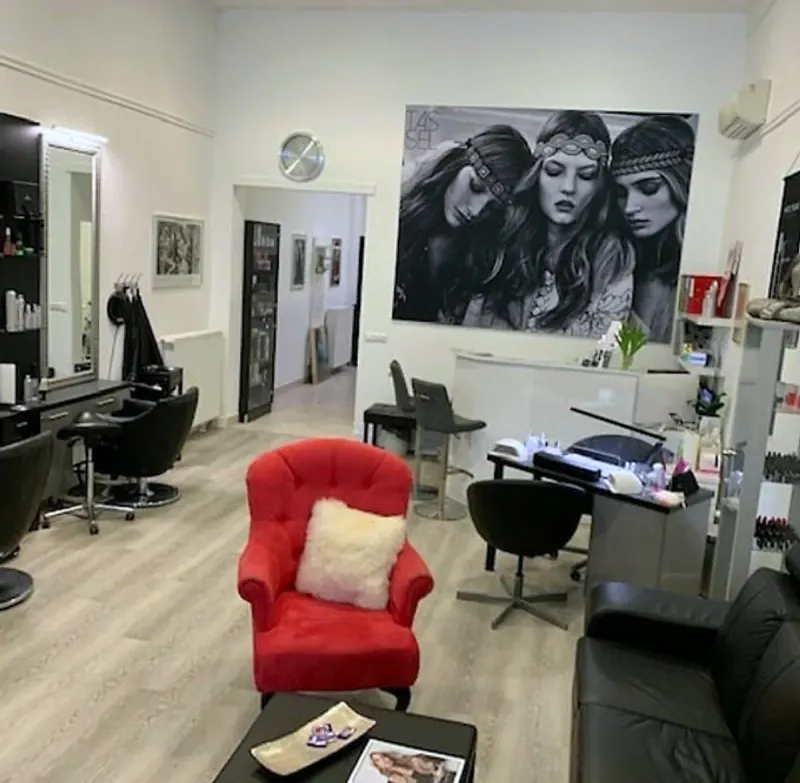 Lounge-Bereich mit rotem Sessel und Empfang im Q LOUNGE Beauty Studio